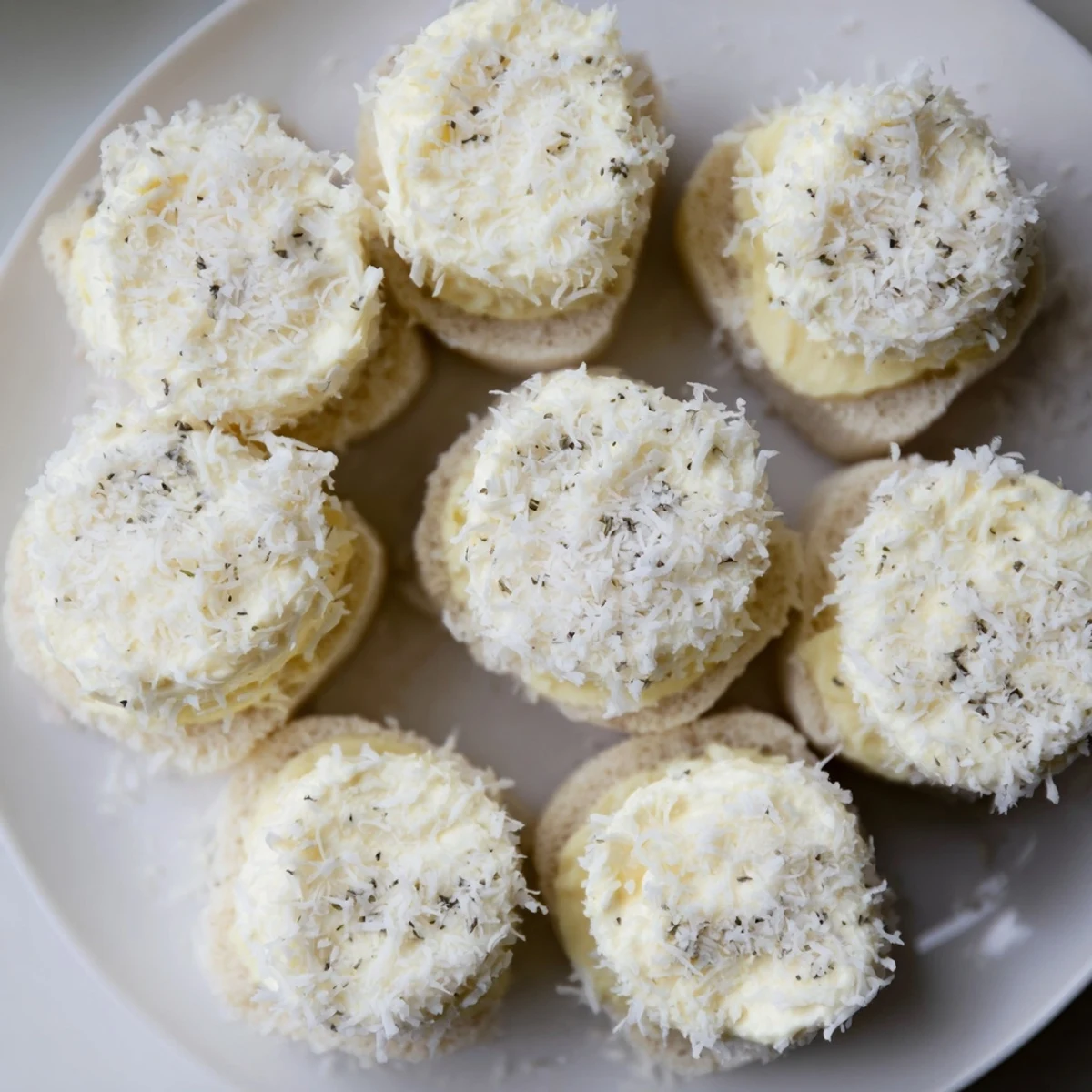 Creamy filling bursting from these snowball tea sandwich bites, lightly dusted with sweet coconut.