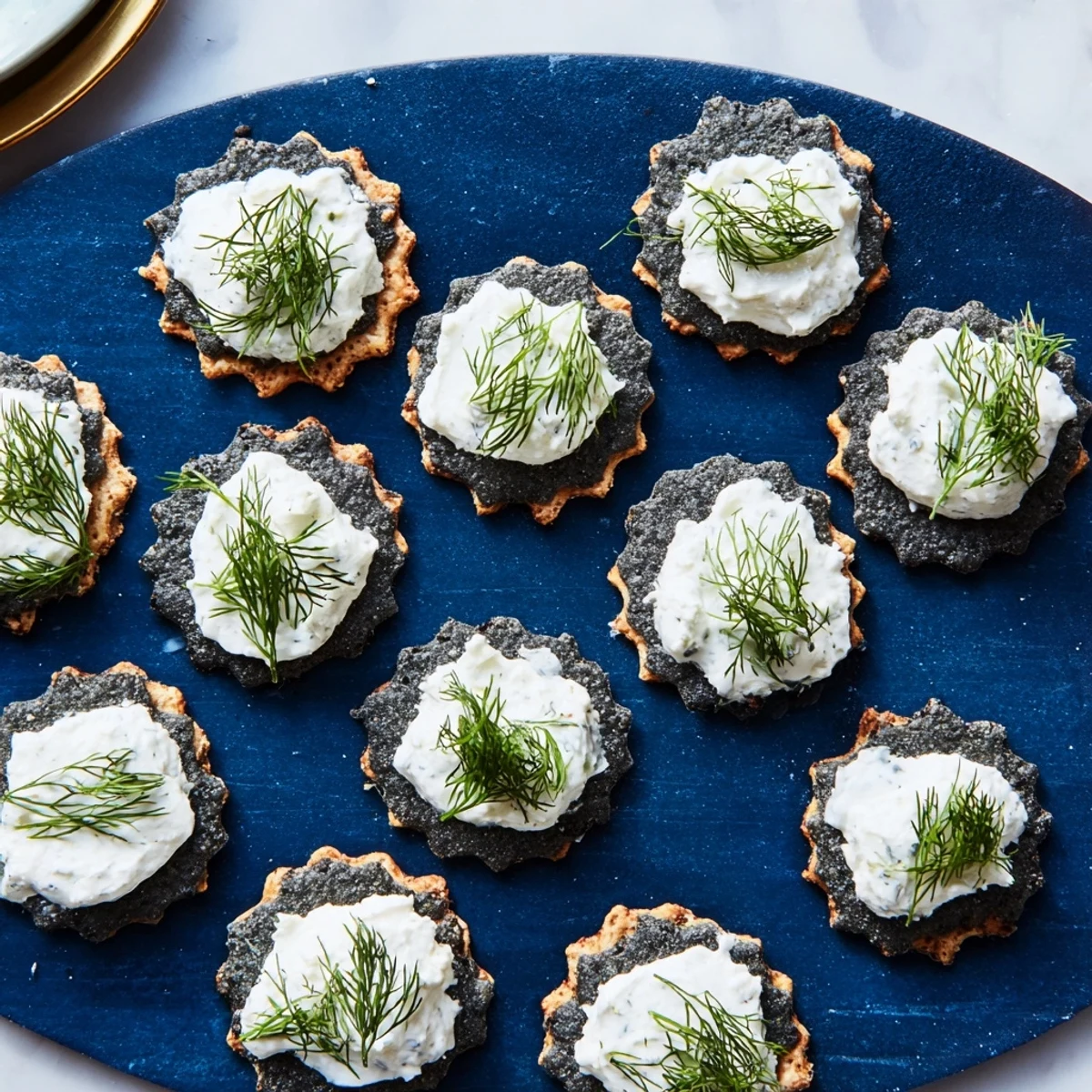 A close-up view of The Stormy Sea appetizer, creamy cheese on dark crackers, garnished with dill.
