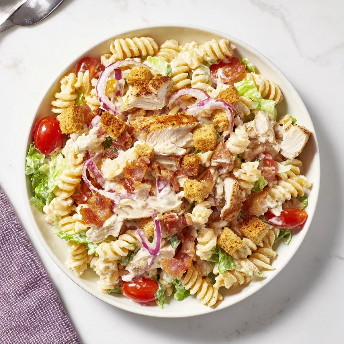 Freshly grated Parmesan is sprinkled over a beautiful bowl of Chicken Caesar Pasta Salad at lunchtime.