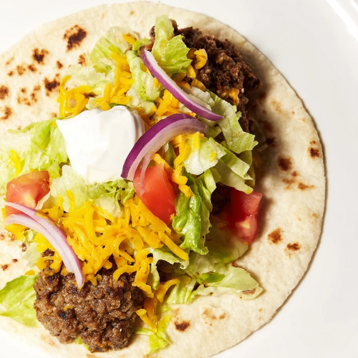 Sizzling Crispy Smash Tacos feature browned ground beef smashed on crispy tortillas, ready to eat.