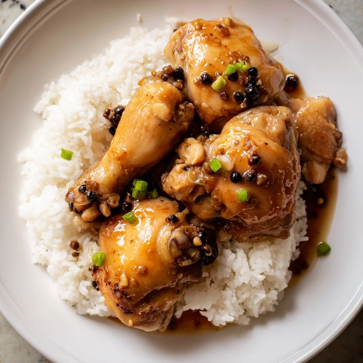 Golden-brown Filipino Chicken Adobo, glistening and served with fluffy white rice, delicious and savory.