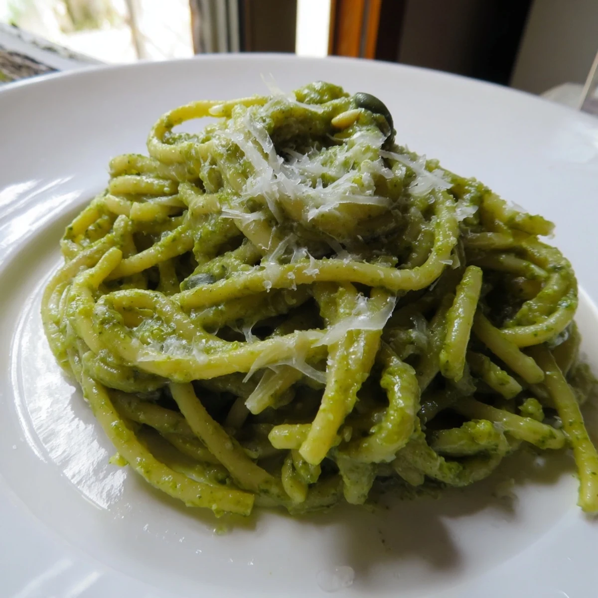 Creamy Sunflower Seed Pesto Pasta served in a rustic white bowl, garnished with shaved Parmesan and a lemon wedge for zest.
