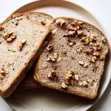 A warm, freshly baked Nutty Whole Wheat Loaf Bread, studded with visible nuts throughout the slices.