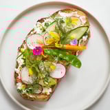 These vegetarian Fresh Meadow Tartines feature vibrant veggies atop herbed cheese on perfectly toasted bread slices.