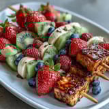 Festive Fourth of July fruit skewers with strawberries, bananas, and blueberries arranged in patriotic red, white, and blue colors.