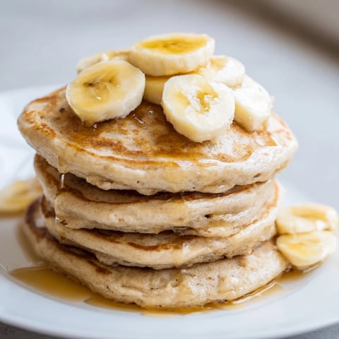 Weekend Golden-Brunch Banana Pancakes stacked high, drizzled with warm maple syrup, perfect for celebrating.