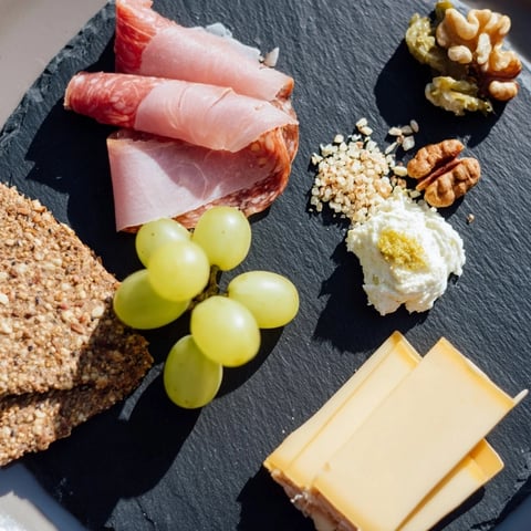Close-up of The Charcuterie Board for One, showcasing savory meats, fine cheeses, and grapes.