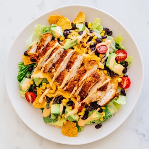A serving of Crunchy Taco Chicken Salad features seasoned sliced chicken, crisp romaine, and diced avocado on a vibrant platter.