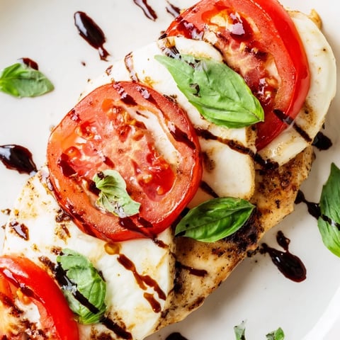 Golden brown chicken breasts topped with melted mozzarella, ripe tomato slices, and fresh basil in a skillet, drizzled with sticky balsamic glaze for an easy Italian-inspired dinner.