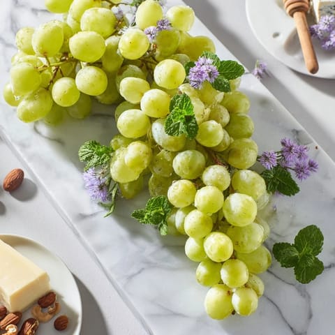 Juicy red and green grapes cascading over a serving board, perfect for a refreshing snack.