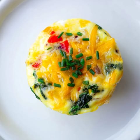 Fluffy Mini Crustless Quiches feature visible spinach and melted cheese; a perfect breakfast bite.