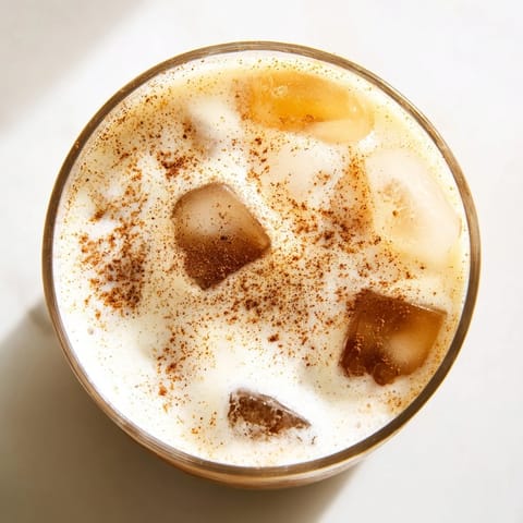 Vibrant iced chai tea with cold foam over ice, garnished with cinnamon, served as a refreshing homemade coffeehouse-style drink.