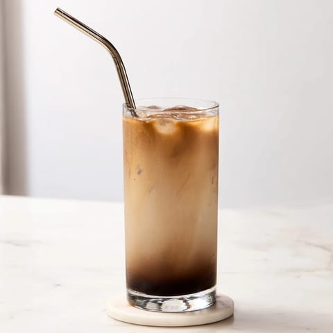 Freshly stirred Milo Ice Latte Hack in a clear glass, with frosty ice cubes and a straw ready for sipping.  