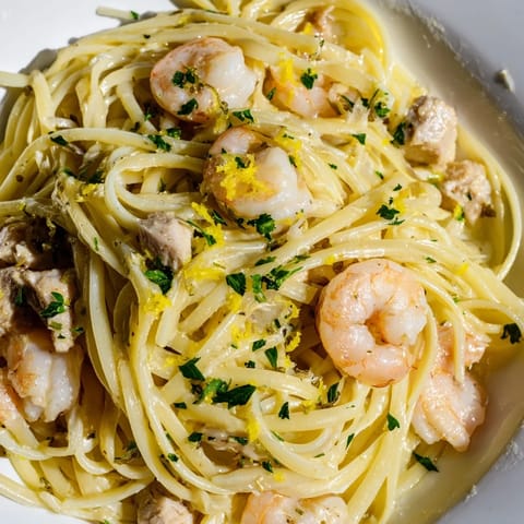 A close-up of Lemon Garlic Shrimp & Chicken Pasta, featuring golden chicken, pink shrimp, and lemon zest.  