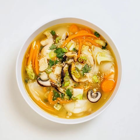 A close-up of Ginger-Miso Winter Soup garnished with toasted sesame seeds and fresh cilantro beside chopsticks.