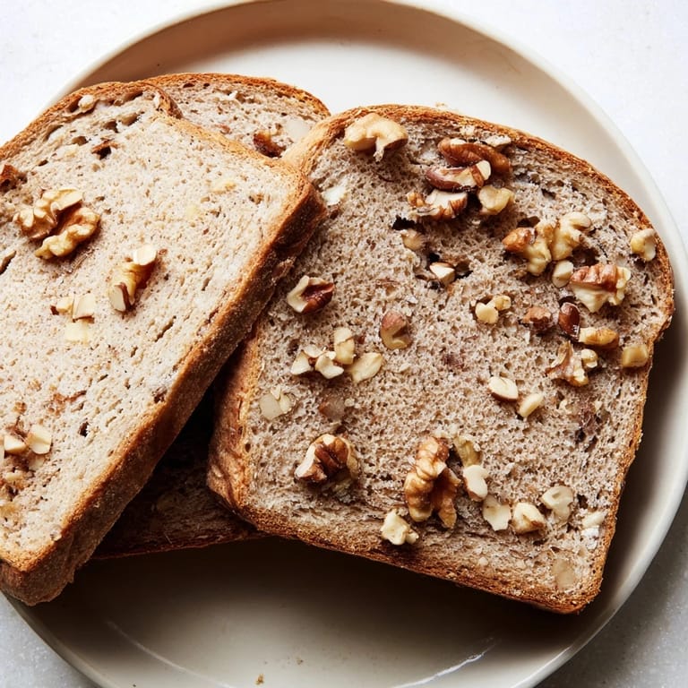 A warm, freshly baked Nutty Whole Wheat Loaf Bread, studded with visible nuts throughout the slices.