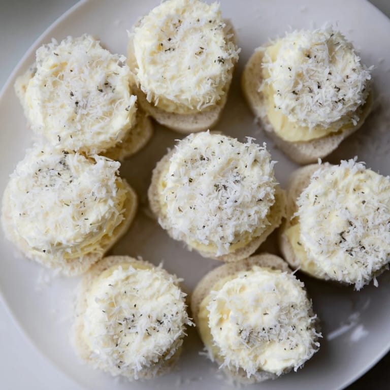 Creamy filling bursting from these snowball tea sandwich bites, lightly dusted with sweet coconut.