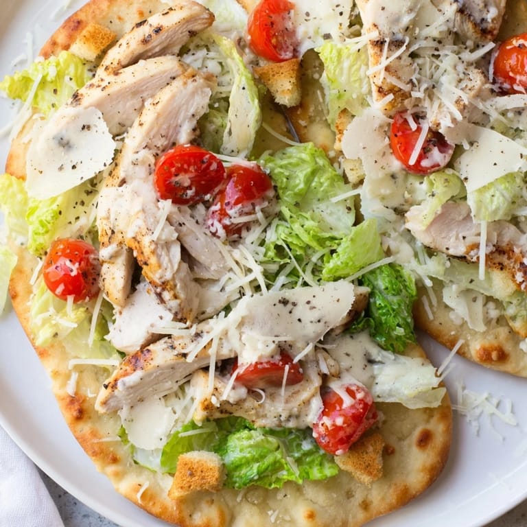 Sliced Chicken Caesar Flatbread with visible chicken, tomatoes, and lettuce; ready for a savory bite.