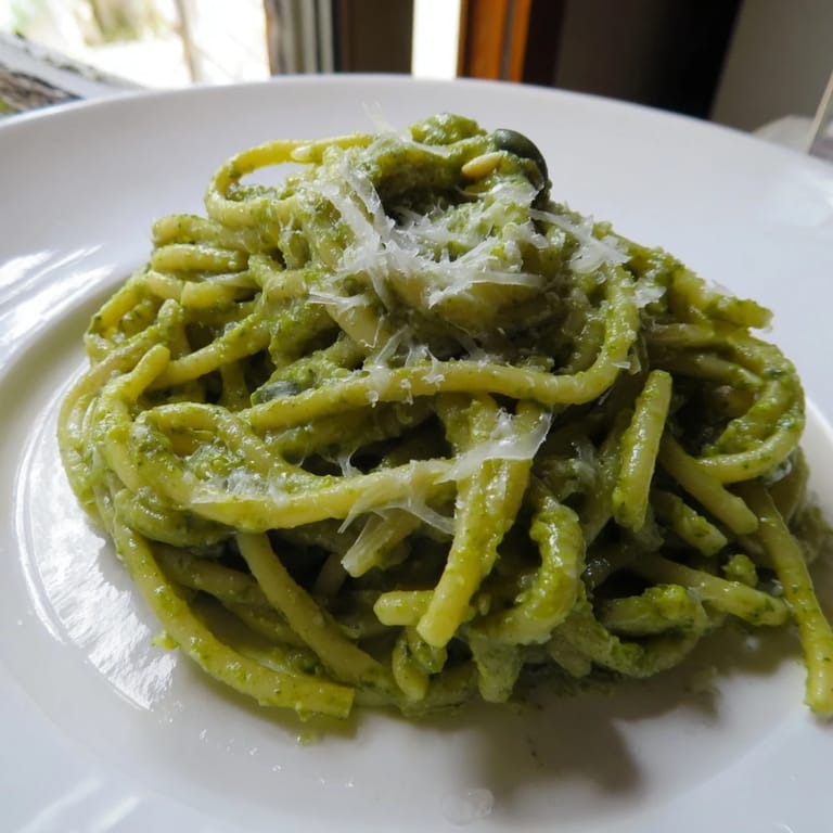 Creamy Sunflower Seed Pesto Pasta served in a rustic white bowl, garnished with shaved Parmesan and a lemon wedge for zest.