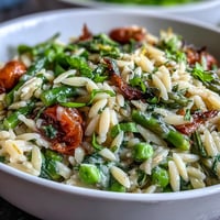 Vibrant Spring Orzo Primavera with fresh asparagus, peas, and parmesan in a light lemon butter sauce.